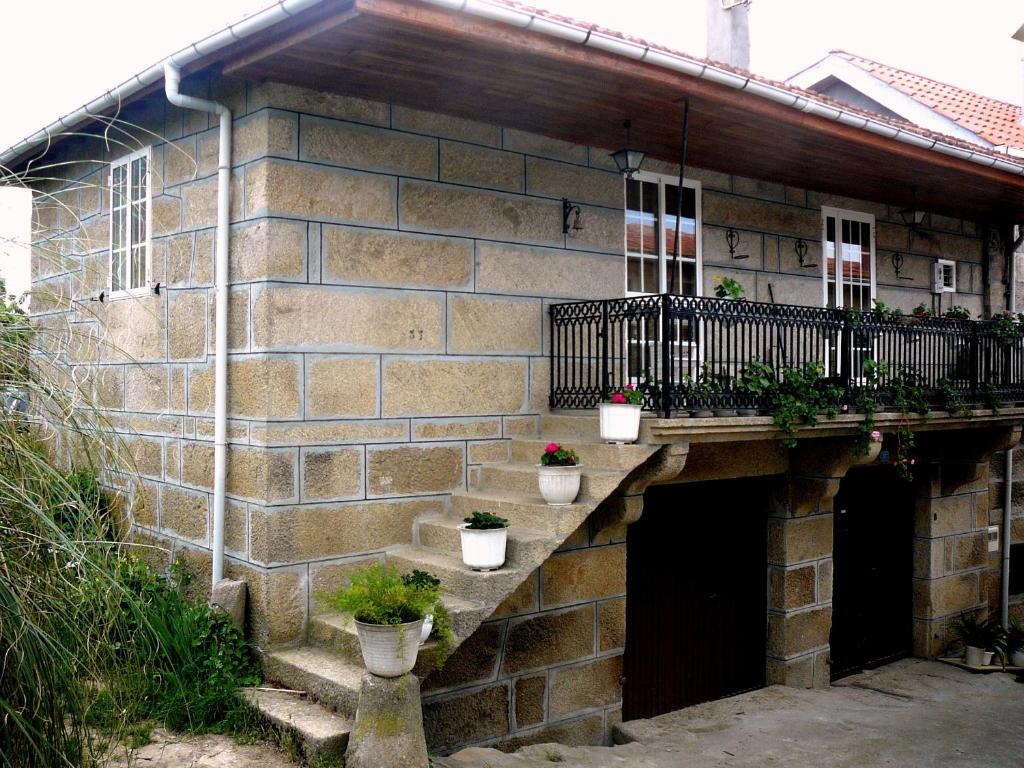 um edifício de tijolos com vasos de plantas numa varanda em Apartamentos Turísticos Casa dos Pulidos em Olás de Villariño