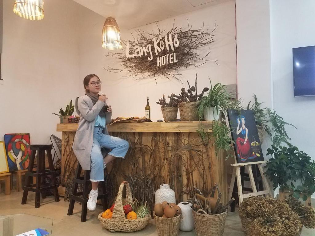 a woman sitting on a counter in a room with plants at Làng Kò Hơ hotel in Da Lat