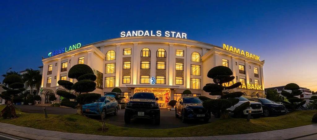 a large building with cars parked in front of it at Sandals Star Hotel in Ðưc Trọng