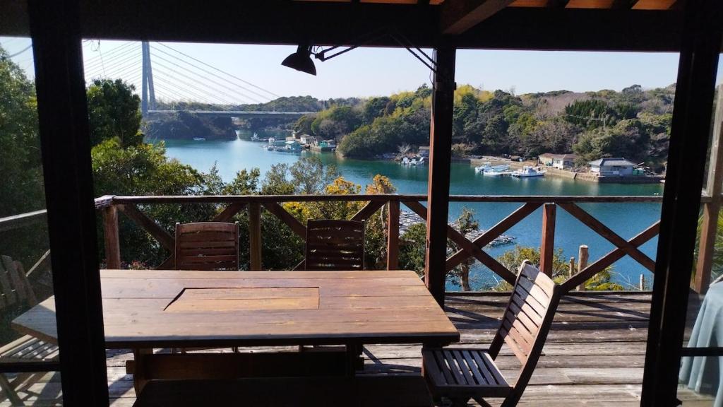 a wooden table on a porch with a view of a river at Cozy Koharuka in Shima