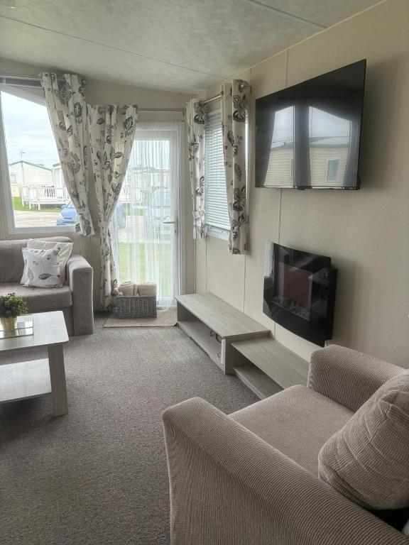 a living room with a couch and a tv at Beach Retreats, Romney Sands, Parkdean Resorts in Greatstone