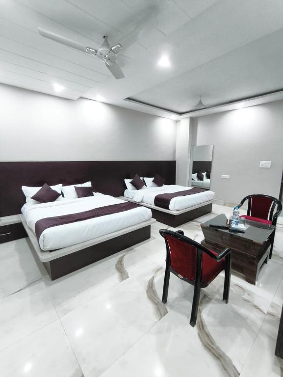 a bedroom with two beds and a chair and a table at Hotel Golden Olive in Kurukshetra