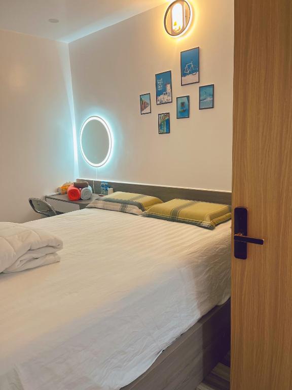 a bedroom with a large bed with a light on the wall at Êm Attic Hai Phong Old Town in Hai Phong