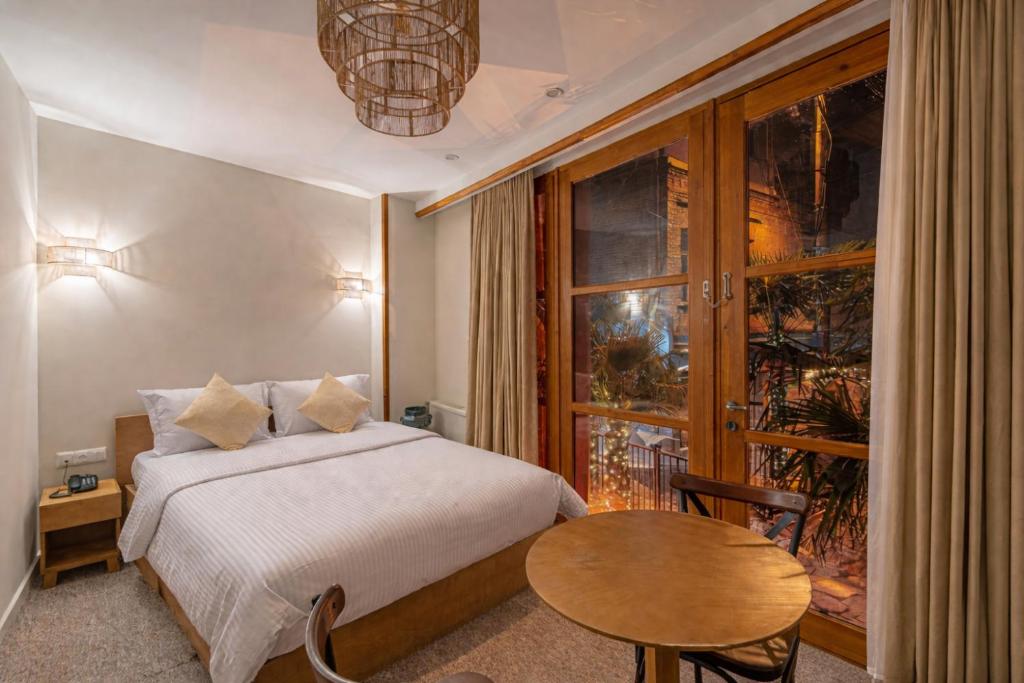 a bedroom with a bed and a table and a window at Palm Tbilisi Boutique Hotel in Tbilisi City