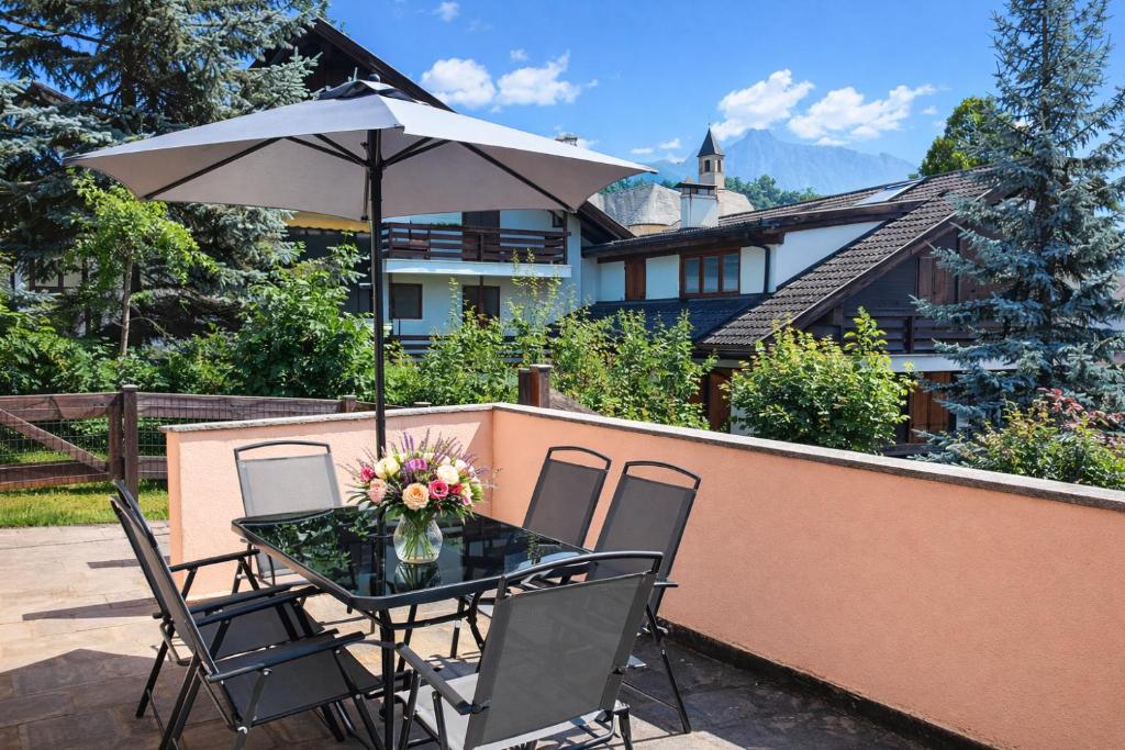 a table and chairs with an umbrella on a patio at CASA DOLOMIA - 3 camere, 2 bagni, parcheggio Dolomiti Affitti in Cavalese