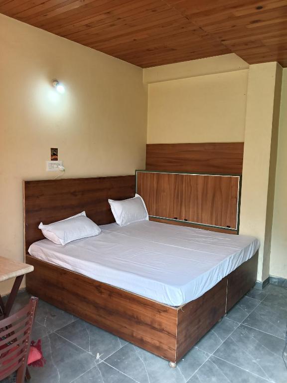 a bedroom with a large bed with a wooden headboard at Divine homestay in Kukri Ser