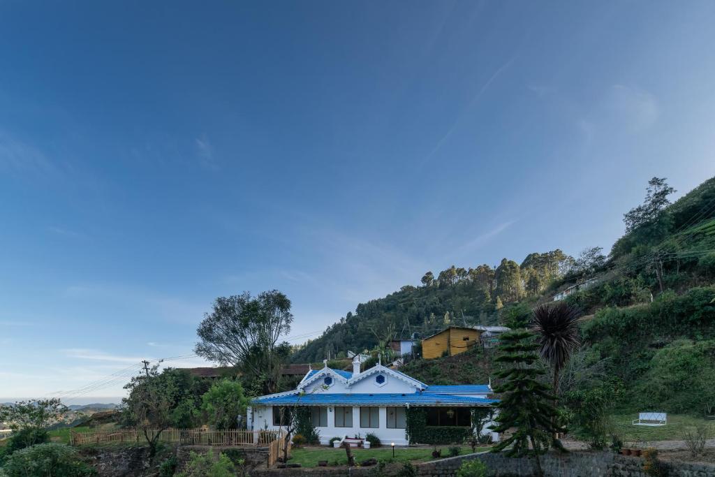 a house with a blue roof on a hill at Hideaway Art Residency in Ooty