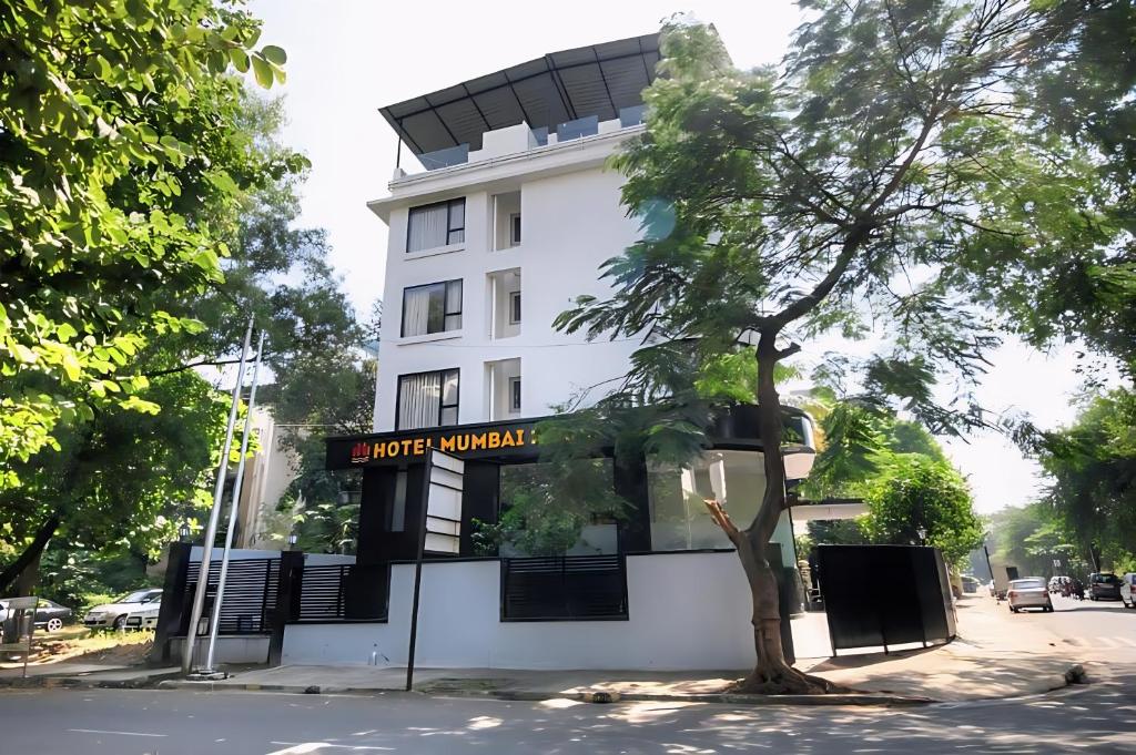 a white building with a tree in front of it at Hotel Mumbai House Ghansoli, Navi Mumbai in Navi Mumbai