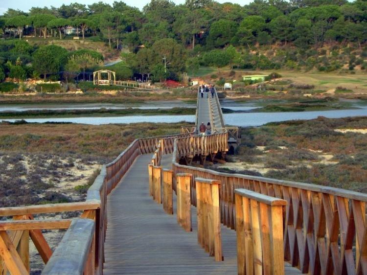 um grupo de pessoas a atravessar uma ponte de madeira em Formosa Villas na Quinta do Lago