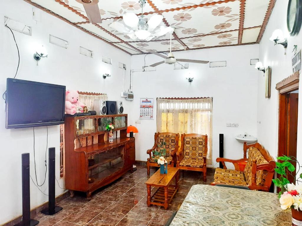 a living room with a tv and some chairs at JP Rest House in Trincomalee