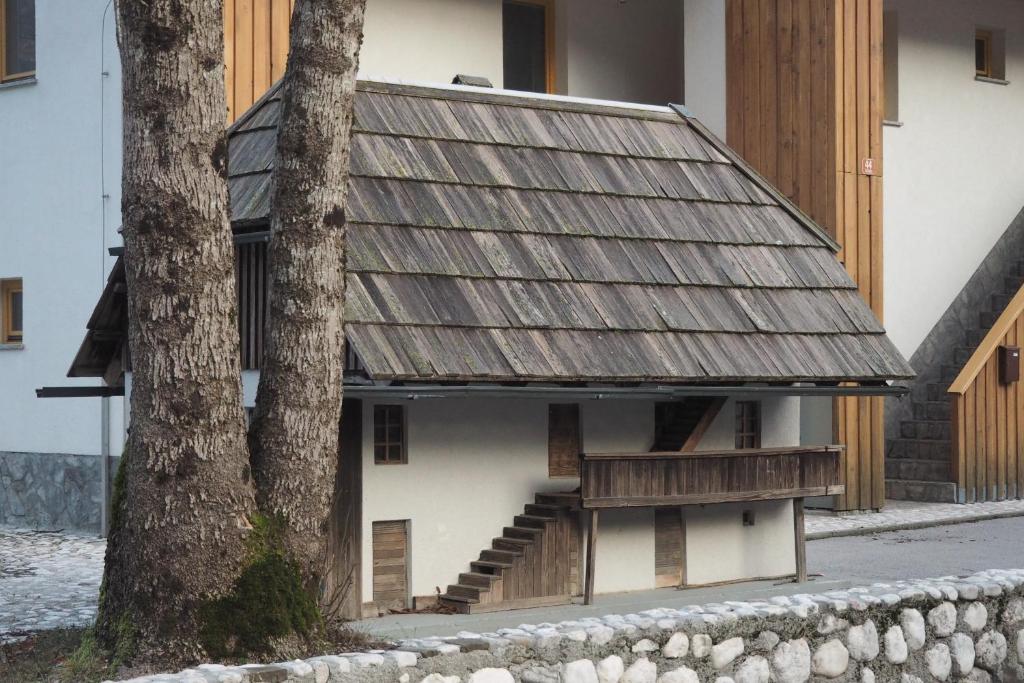 ein Gebäude mit einem Metalldach neben einem Baum in der Unterkunft Apartment Ajda in Bovec