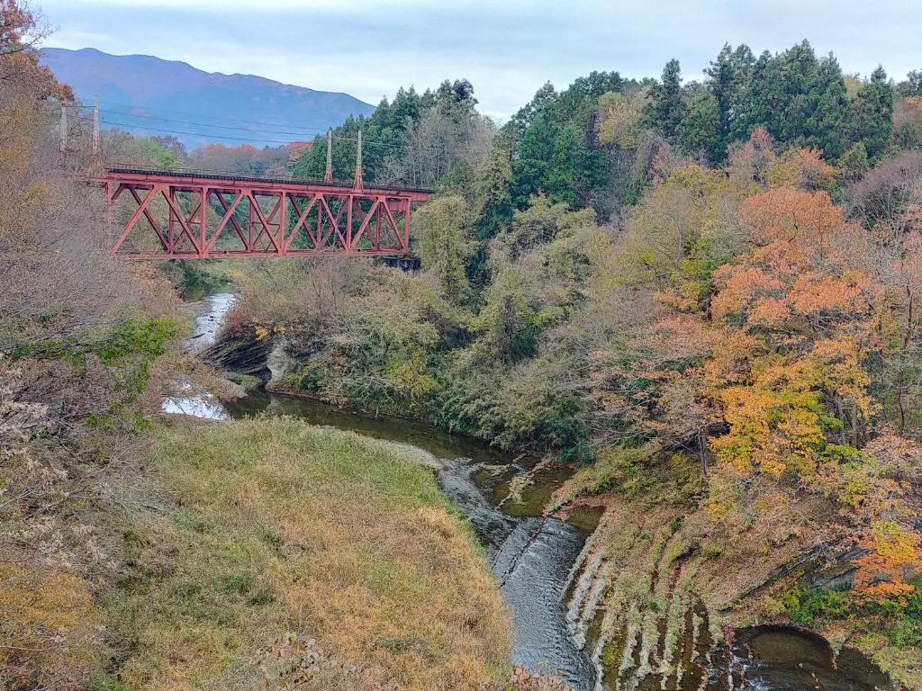 a red bridge over a river in a forest at Suijinhotel in Tochiya