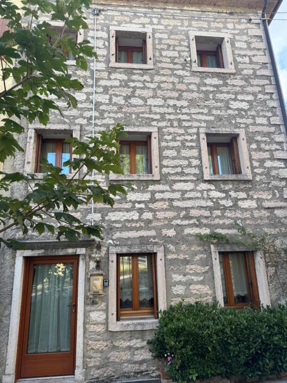 a tall stone building with many windows on it at Alloggio ai Campanari in Conco