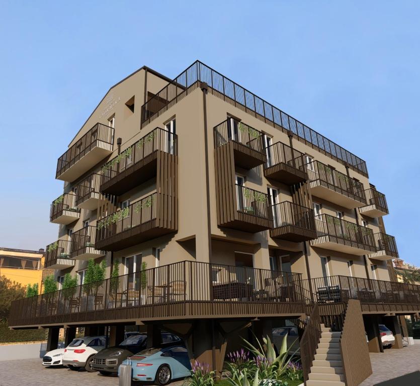 a building with balconies and cars parked in a parking lot at Hotel Taormina in Bardolino