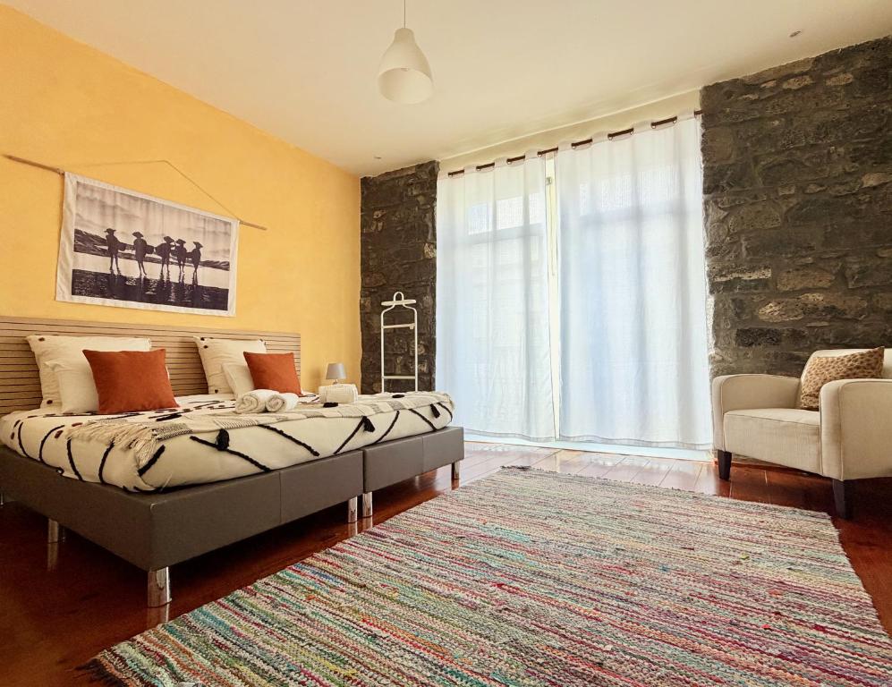 a bedroom with a bed and a couch and a rug at A-Típica GuestHouse in Ponta Delgada