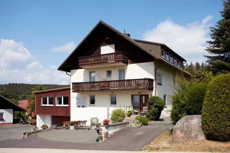 a large white building with a brown roof at Pension KaraMia in Fichtelberg
