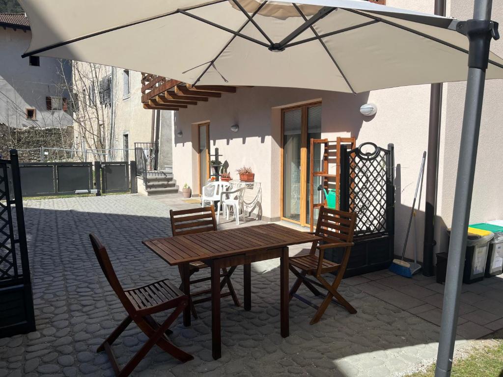 a wooden table and chairs under an umbrella on a patio at Ca' Bertera in Ledro