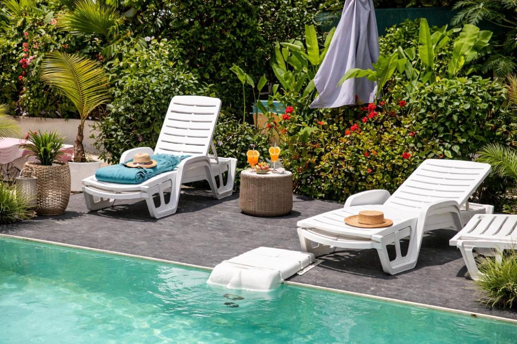 two chairs and a table next to a swimming pool at La Baraka in Dzaoudzi