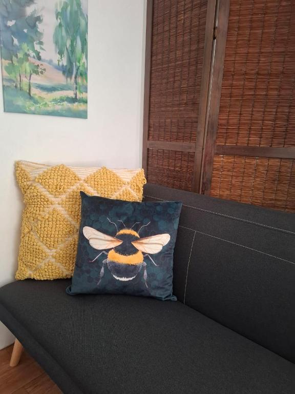 a black couch with a pillow with a bee on it at Melrose Garden Cottages - Hibiscus Cottage in Durban