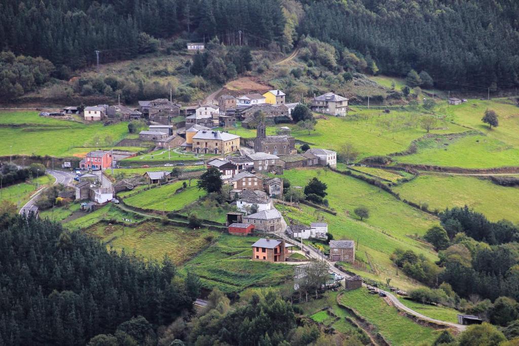 un pequeño pueblo en una colina verde con casas en Casa Aniceto, en Taramundi