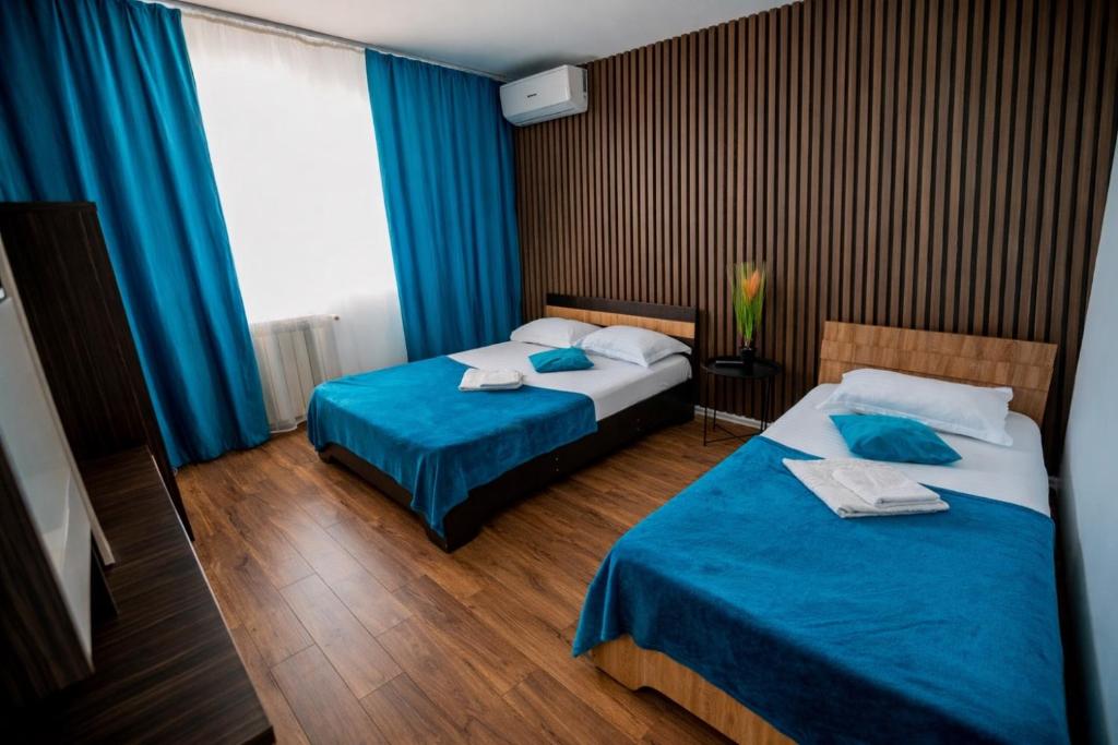 two beds in a hotel room with blue curtains at Pensiunea Gerard 2 Mai Camere Moderne cu baie privata, la 250 M de plaja ,Foisor, Parcare & WIfi Gratuit in 2 Mai