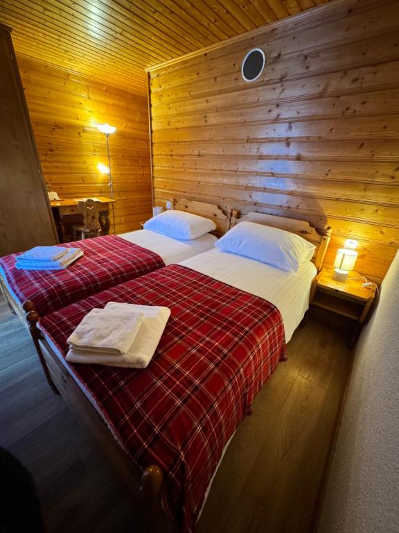 two beds in a room with wooden walls at Hotel La Tour d'Aï in Leysin