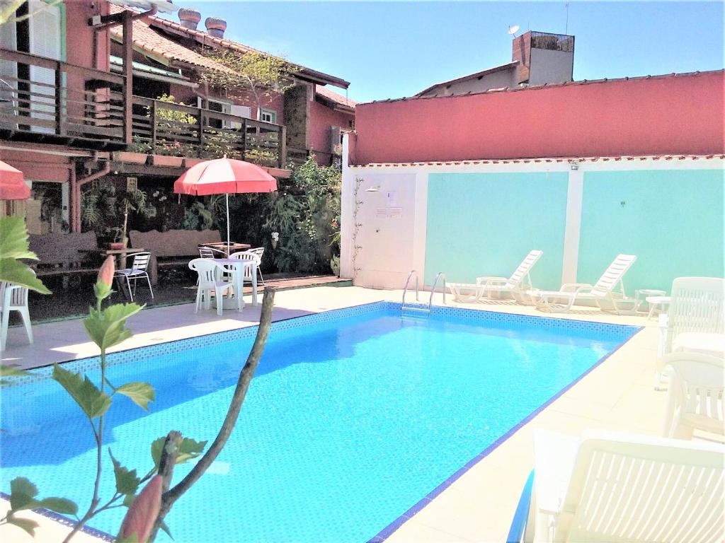 a swimming pool with chairs and a table and an umbrella at Pousada Irashai in Juquei