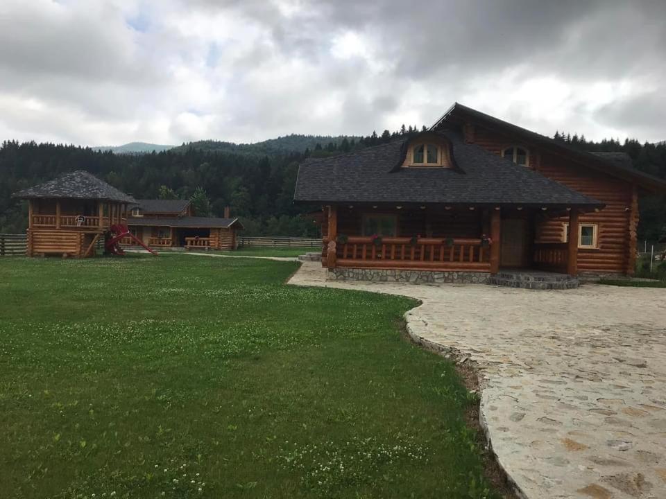 a log cabin with a grassy yard in front of it at Cabana Goralilor in Mănăstirea Humorului
