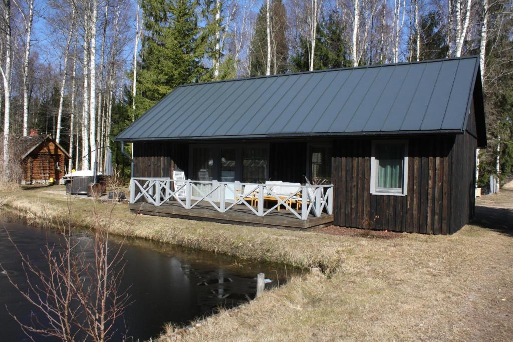 a cabin with a table and chairs next to a body of water at Berzlejas 3 in Upesgrīva