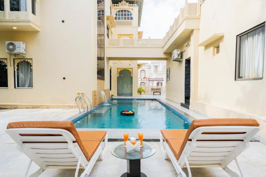 a pool in a house with two chairs and a table at Virasat-1969 in Udaipur