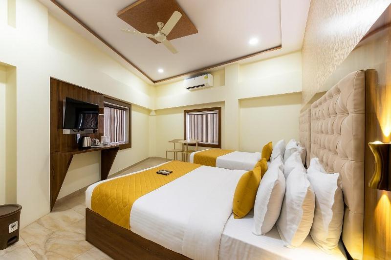 a bedroom with a large white bed with yellow and white pillows at Imperial Hotel Near Haji Ali in Mumbai