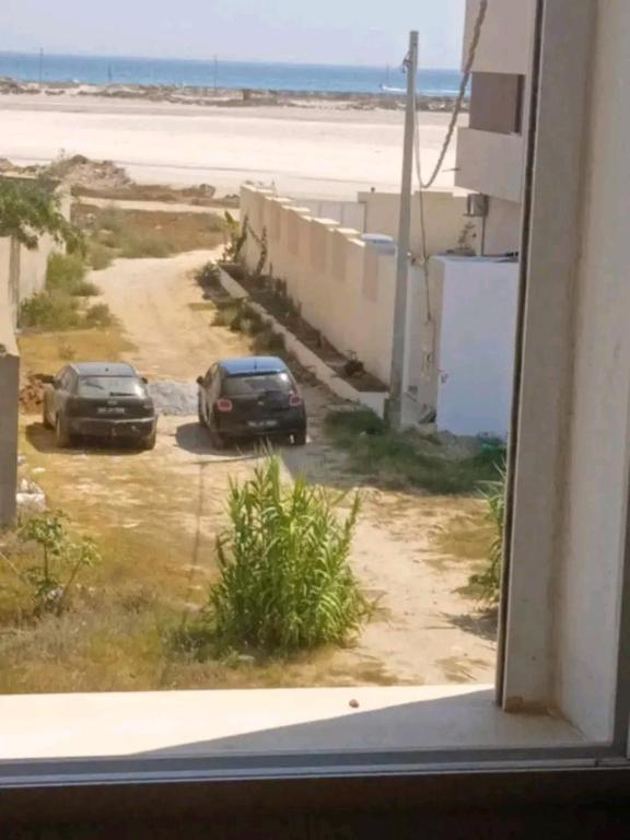 two cars parked in a parking lot next to the beach at Romantique place in Mahdia
