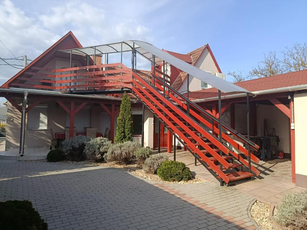 a house with a red staircase on the side of it at Róma Apartmanház in Bogács