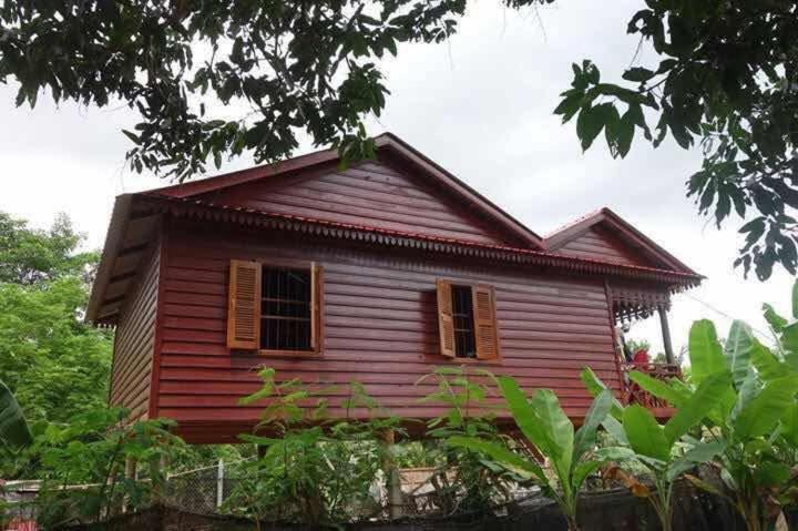 a red house with two windows and a tree at Authentic Cambodian Angkor Cottage in Siem Reap