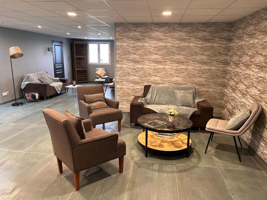 a waiting room with couches and chairs and a table at Contact Hotel Utah Beach Carentan in Carentan