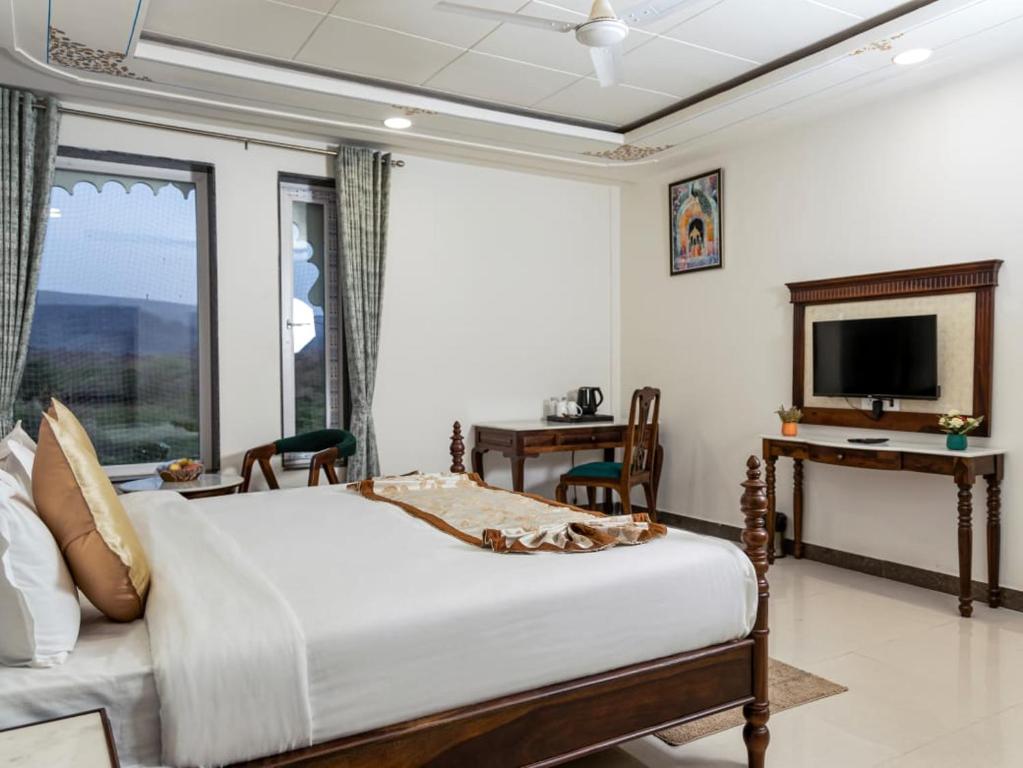 a bedroom with a bed and a television and a desk at Jaisamand Garh Resort in Udaipur