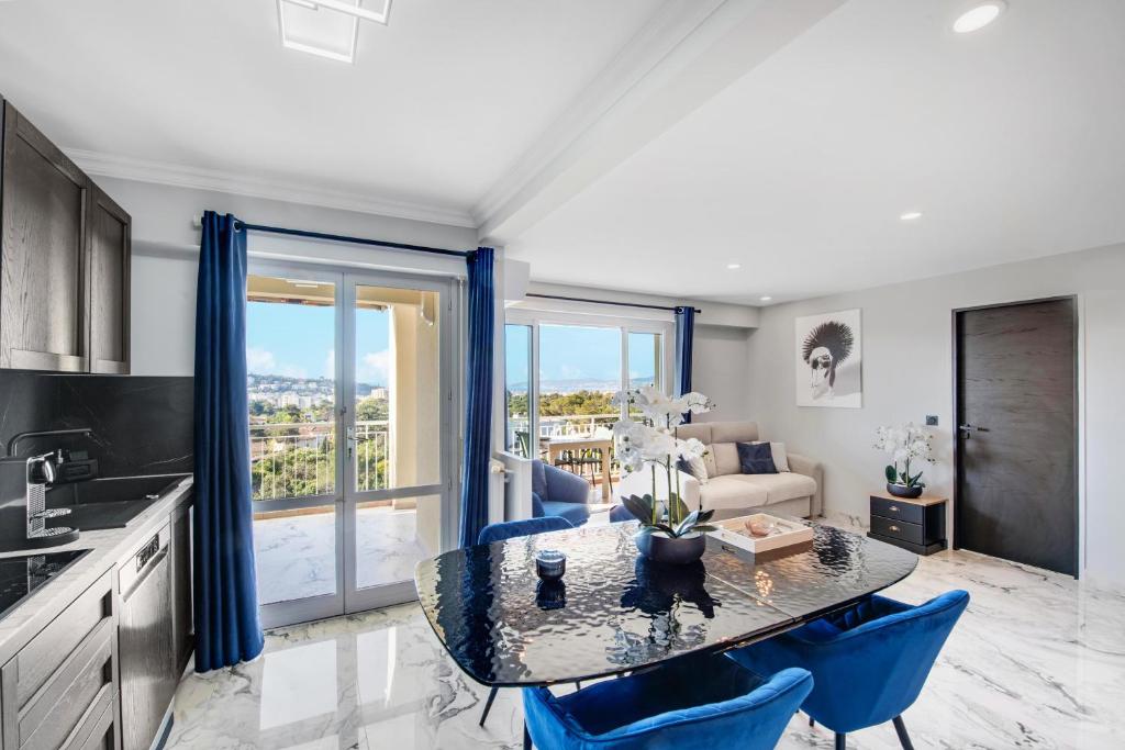 a kitchen and living room with a table and blue chairs at Panorama Majestic in Saint-Raphaël
