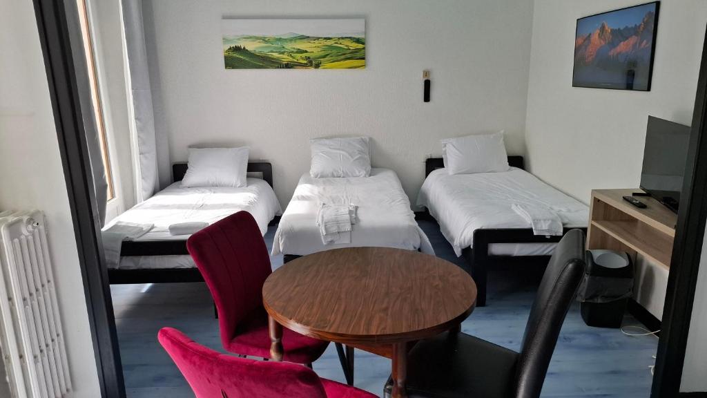 a room with two beds and a table and chairs at Chambre quadruple in Lully