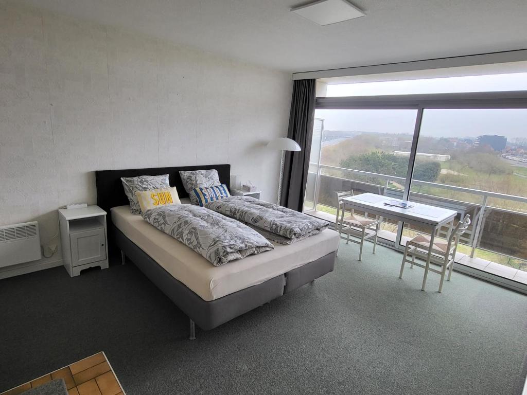 a bedroom with a bed and a table and a window at Studio Residentie Astrid Bredene in Bredene