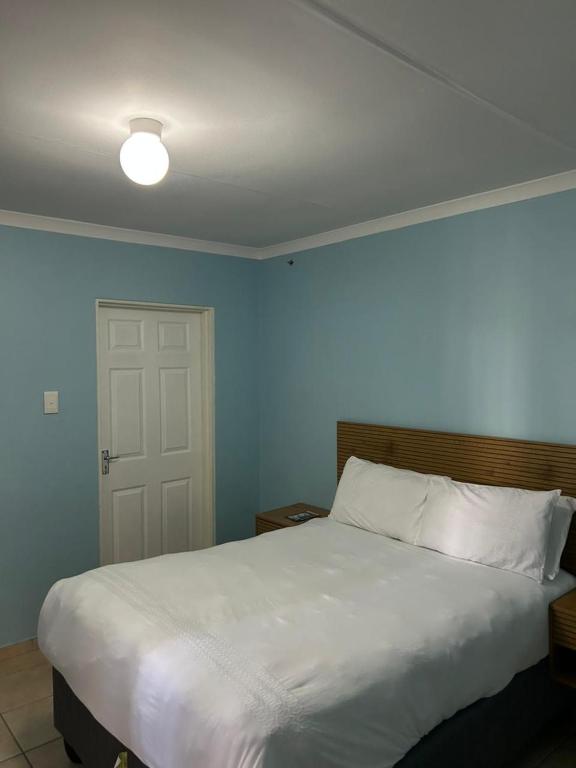 a bedroom with a large white bed and a door at Masakwe BNB in Soweto