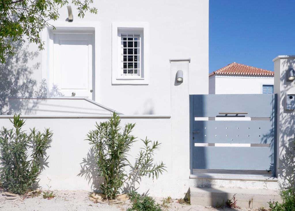 a white house with a blue door and plants at Modern Sea-View Maisonette in Spetses for 6 people in Spetses