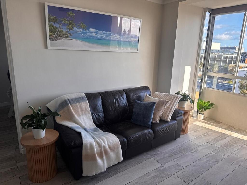 a black leather couch in a living room with a window at Ekaya in Fremantle