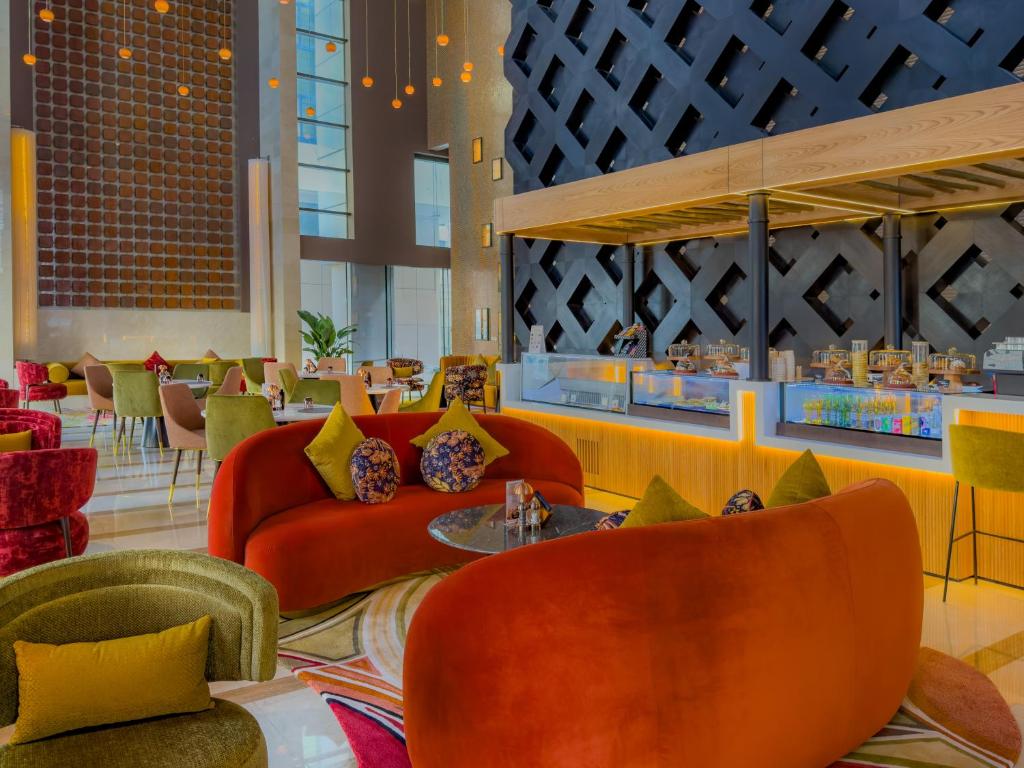 a lobby with orange couches and tables and chairs at Southern Sun Abu Dhabi in Abu Dhabi
