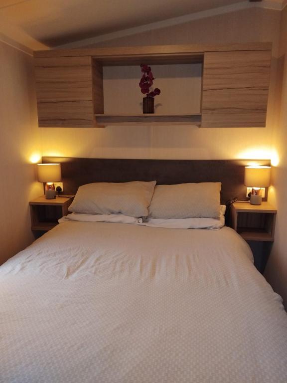 a bedroom with a large white bed with two lamps at Sunny sands retreat in Skipsea