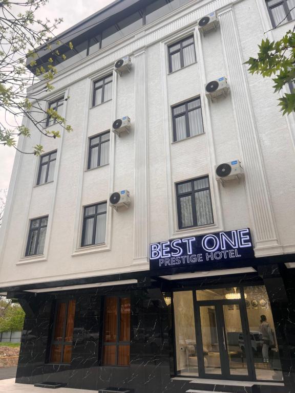 a white building with a sign that reads best one tastes their hotel at Best One Hotel in Jizzax