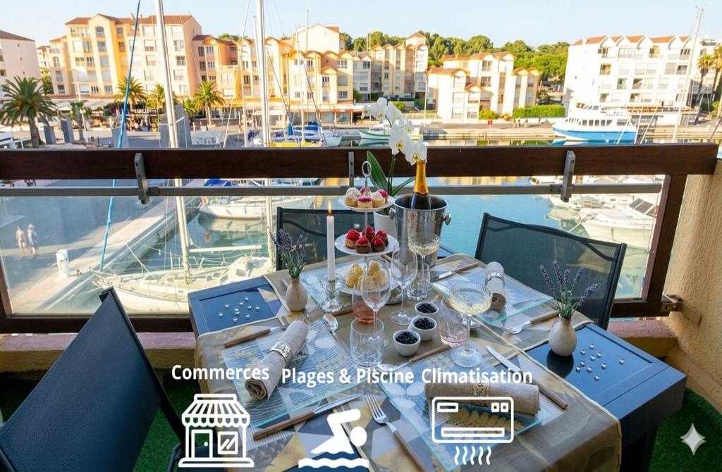 a table on a balcony with a view of a marina at Merveilleuse Port - Piscine - Plage - Climatisation - Commerces in Gruissan