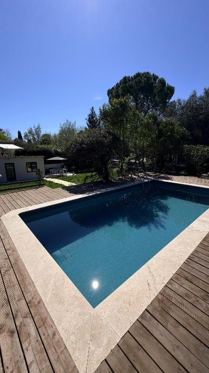 a large swimming pool on a deck with a wooden deck at Mazets sous le pin in Le Rouret