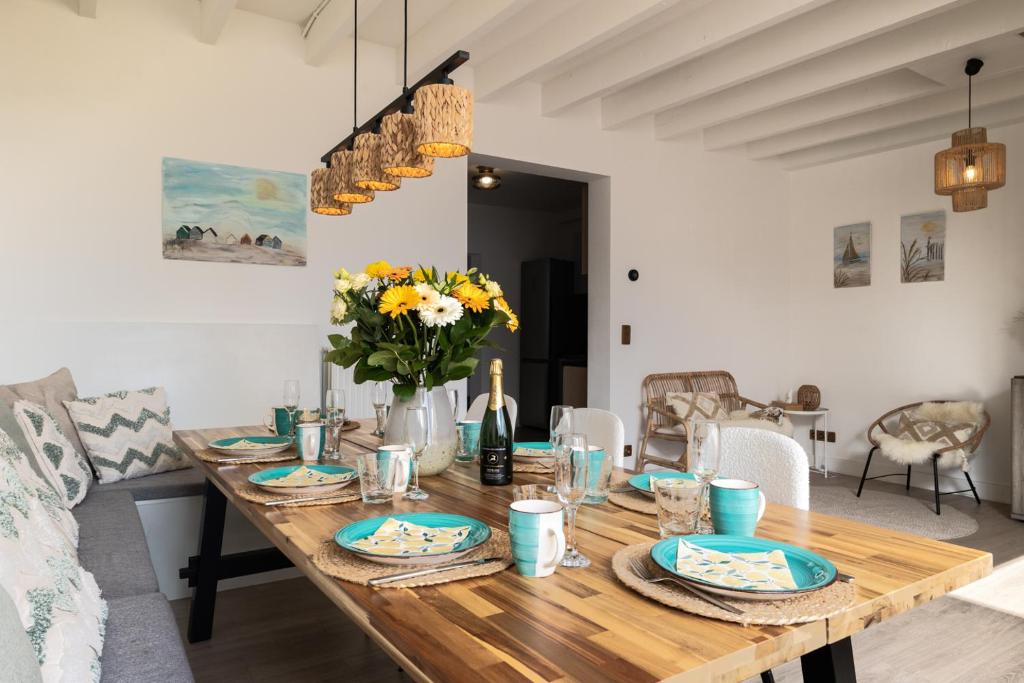 a dining room with a wooden table with flowers on it at Warvinge 73 in De Haan
