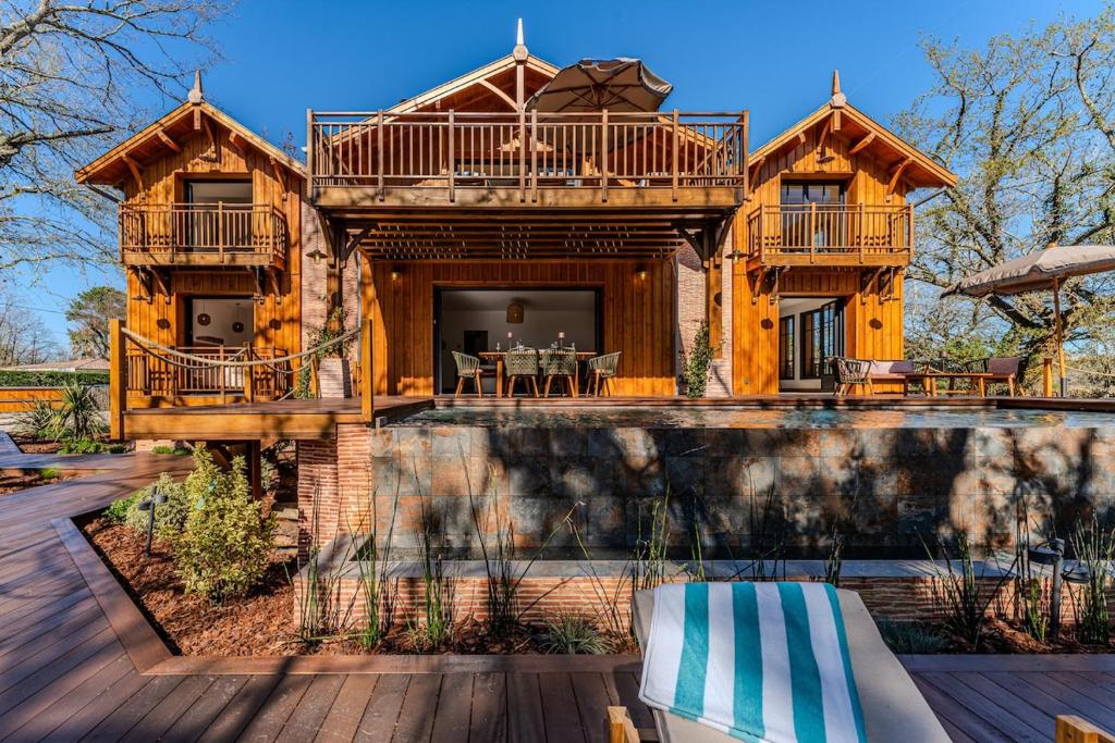 a log house with a deck and a pool at Villa Saint Brice, frontline in Arès