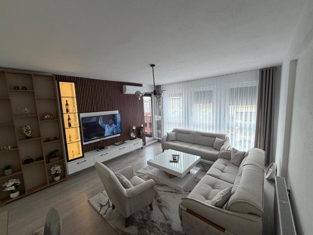 a living room with a couch and chairs and a tv at Eda's Home in Mitrovica